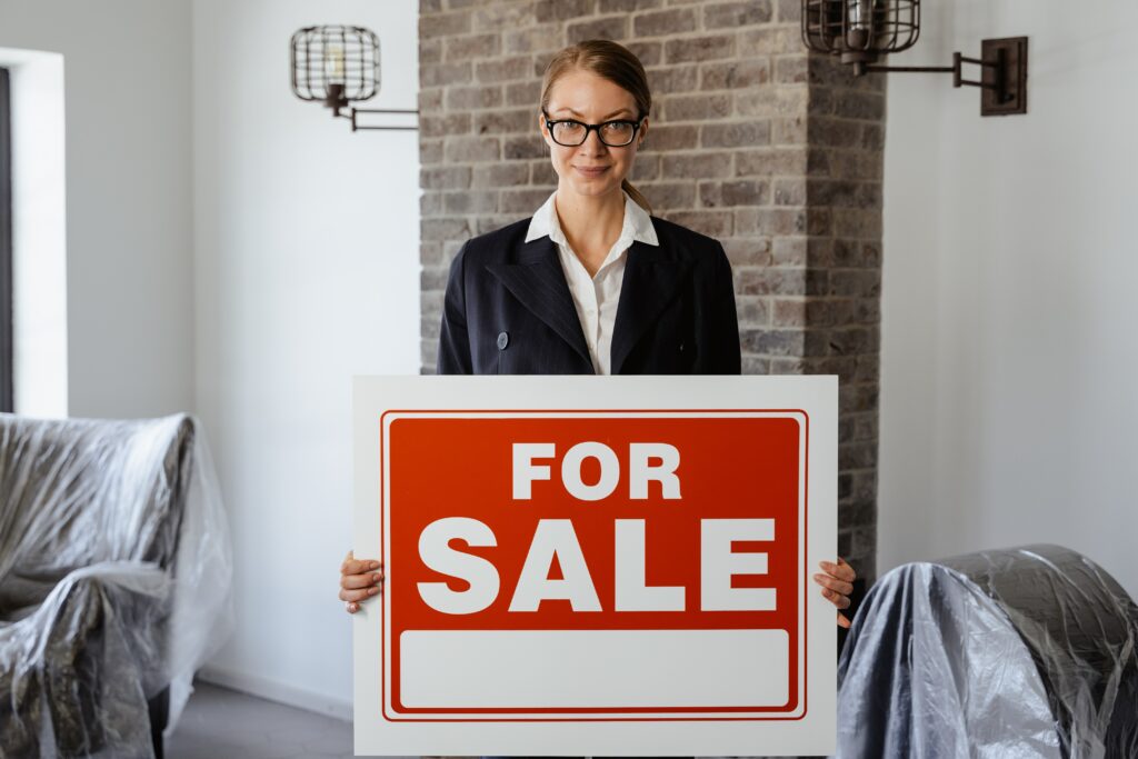 A real estate agent holds a for-sale sign inside a trendy home
